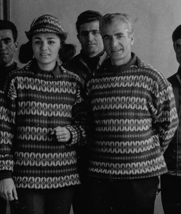 Four adults stand close together, with two in the foreground wearing matching patterned sweaters — a public domain photograph from The Shah of Iran archive documenting the Pahlavi era.