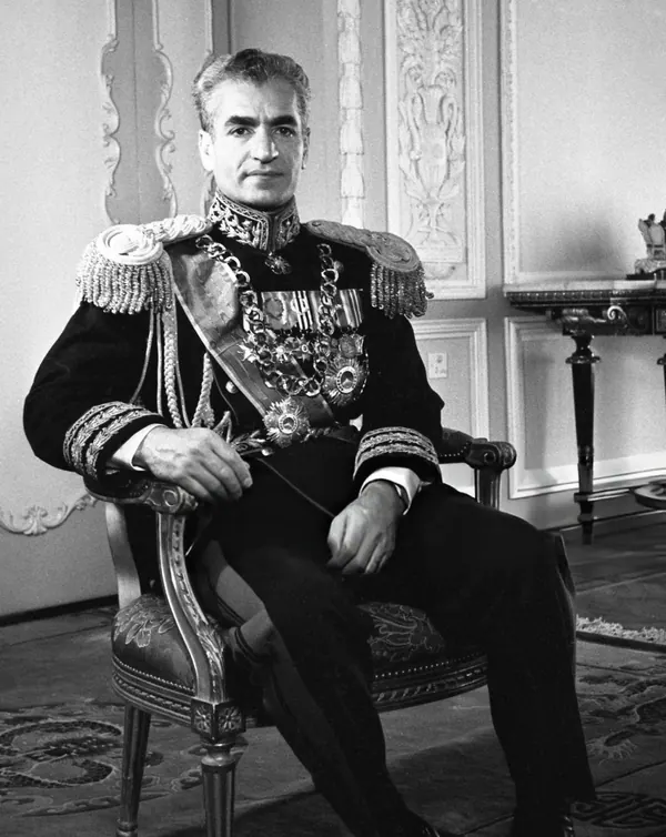 His Majesty, the Shah of Iran in a decorated military uniform sits in an ornate chair within a formal room — a public domain photograph from The Shah of Iran archive documenting the Pahlavi era.