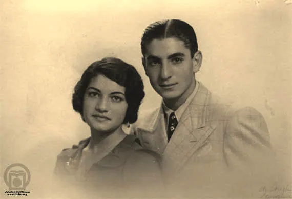 A young man in a light-colored suit and Farah Pahlavi, Empress of Iran, in a dark jacket pose together — a public domain photograph from The Shah of Iran archive documenting the Pahlavi era.